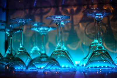 Close-up of wineglasses arranged on illuminated shelf in bar