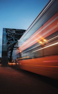 Blurred motion of bus moving on bridge against clear sky during sunset