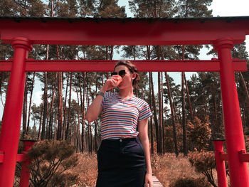 Young woman wearing sunglasses standing against trees