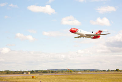 Airplane flying over field against sky