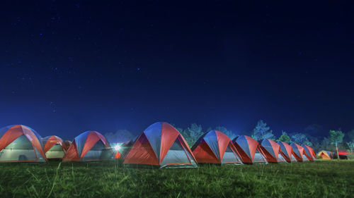 Multi colored umbrellas on field against clear sky at night