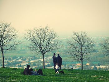 Rear view of people on field against clear sky