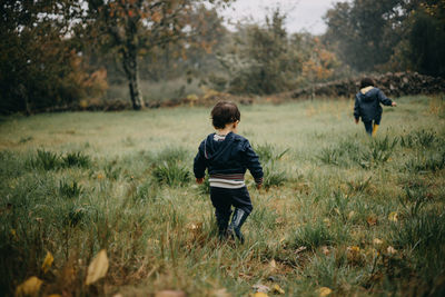 Rear view brother and sister playing in the grass