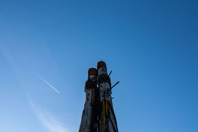 Low angle view of wooden post against clear blue sky