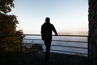 Rear view of man standing at observation point against sky