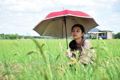 Woman holding umbrella on field