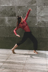 Full length of woman dancing on floor against wall