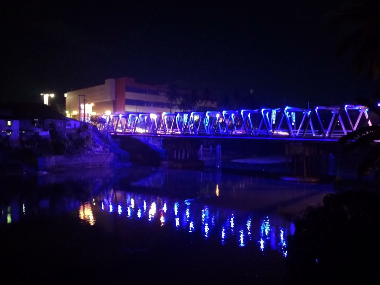 ILLUMINATED BRIDGE OVER RIVER IN CITY