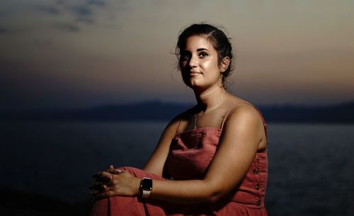 Portrait of woman standing against sea at sunset