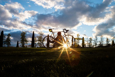 Silhouette man with bicycle on field