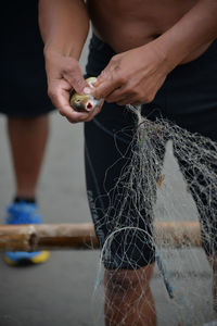 Midsection of man removing fish from fishing net