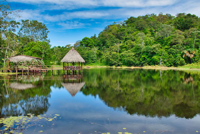 Scenic view of lake by trees and building against sky
