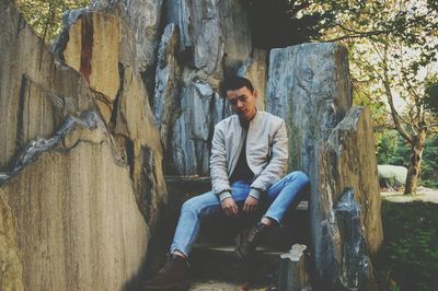 Full length portrait of young man sitting on steps at park