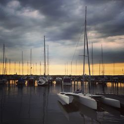 Boats moored in harbor at sunset