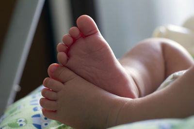 Low section of newborn baby relaxing on bed at home