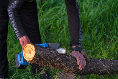 Low section of man standing on tree trunk