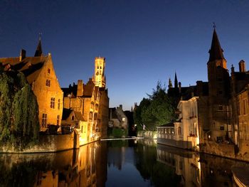 Canal amidst buildings against clear sky at night