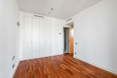 Interior of empty apartment, white room with built-in wardrobe and parquet floor