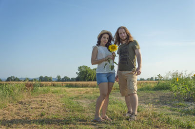 Full length of young couple standing on field against sky