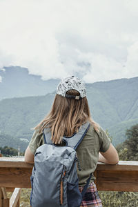 Rear view of woman standing on mountain against sky