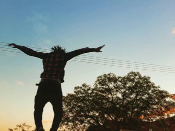 Low angle view of person standing by tree against sky