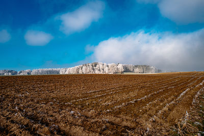 Scenic view of agricultural field against cloudy sky during winter