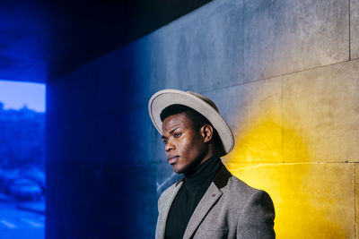 Portrait of young man looking away against wall