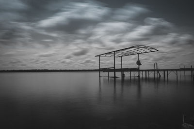 Pier on sea against cloudy sky