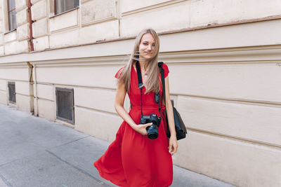 Portrait of smiling young woman standing against building