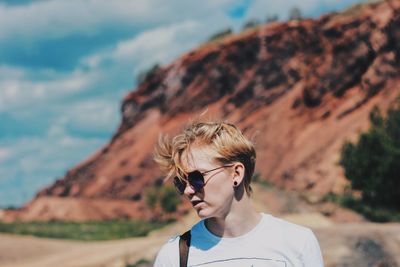 Young woman wearing sunglasses on mountain against sky