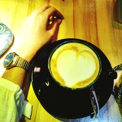 Close-up of hand holding tea cup on table