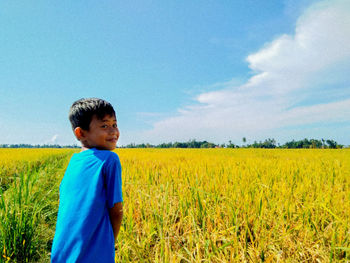 Boy standing on field against sky