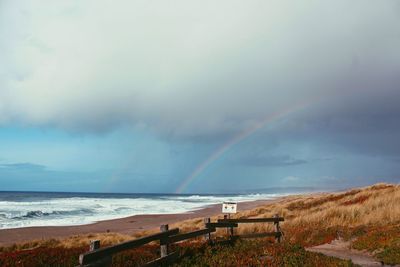 Scenic view of sea against rainbow in sky