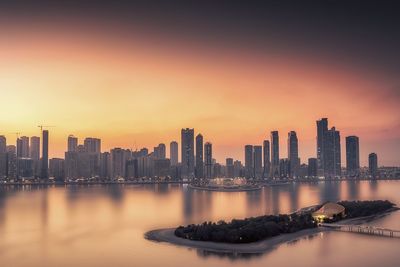 Illuminated buildings in city against sky during sunset