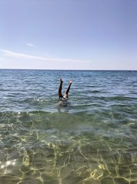 Rear view of man jumping in sea against clear blue sky