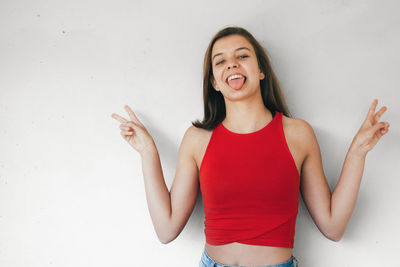 Portrait of a smiling young woman standing against wall