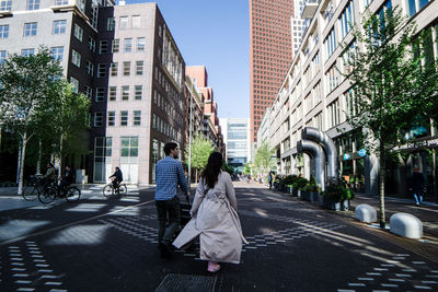 Rear view of people walking on street in city