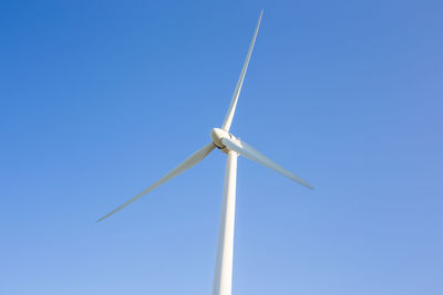 Low angle view of wind turbine against blue sky