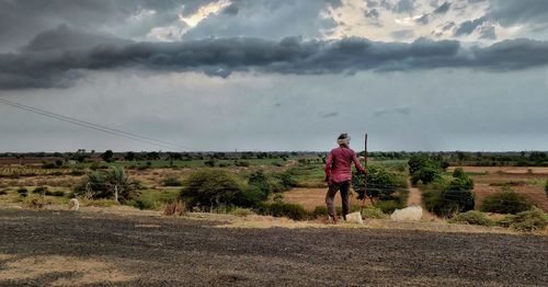 Rear view of man walking on road against sky