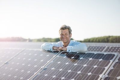 Smiling mature man standing in solar plant