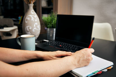 Cropped image of hand holding coffee cup on table