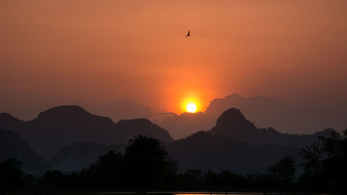 Scenic view of silhouette mountains against orange sky