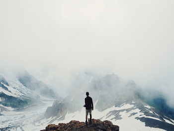 Man standing on snow covered mountain against sky