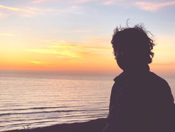 Woman looking at sea against sky during sunset