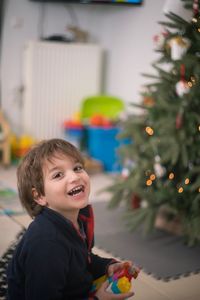 Caucasian boy smiling in front of christmas tree at home