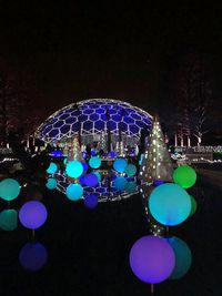 Illuminated christmas lights at amusement park against clear sky at night