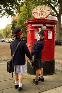 Full length of students in uniform standing by mailbox