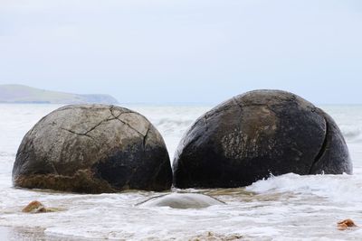 Rocks on beach against clear sky