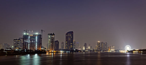 Illuminated buildings in city against sky at night