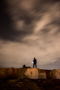 Silhouette man standing on land against sky during sunset